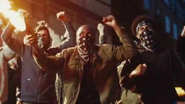 Afrikanska amerikanska manliga rebeller i huva och med maskerat ansikte protesterar mot aggressiv demonstration med Molotov cocktail. Killen med bensinbomb på protest i folkmassan. Folk i upplopp med flaskbomb. — Stockvideo