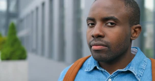 Portret van de jonge Afro-Amerikaanse knappe en vrolijke man die een medisch masker opneemt en naar de camera kijkt. Pandemie van het coronavirus concept. Man die ademhalingsbescherming aanbrengt in de stad. — Stockvideo