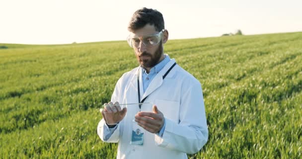 Üveg futuisztikus szerkentyű egy férfi ökológus kezében, aki nyáron terepen állt. Átlátszó eszköz csúcstechnológiás technológiája. Fehér ruhás férfi és szemüveges, aki a jövő tabletjét koppintja. Bővített valóság. — Stock videók