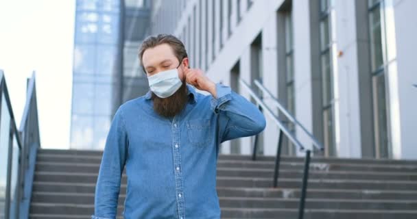 Kafkasyalı yakışıklı, neşeli adamın portresi. Sağlık maskesini çıkarıyor ve Coronavirus gittikten sonra gülümsüyor. Salgın konseptinin sonu. Mutlu erkek, solunum korumasını kaldırıyor. Corona kazandı.. — Stok video