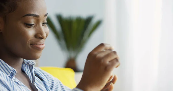 Tırnaklarını ojeyle boyayıp onları izleyen çekici Afro-Amerikan kadının yakın çekimleri. - Evde. İçeride.