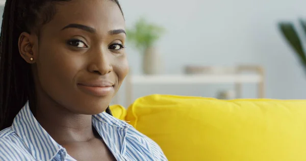 Zbliżenie młodej Afroamerykanki wpisującej na klawiaturze laptopa w domu na żółtej kanapie. Kryty — Zdjęcie stockowe