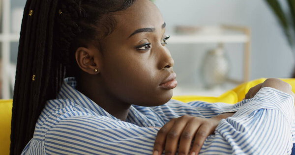 Portrait of the upset African American young woman having a depression and sitting on the sofa at home. Indoor Royalty Free Stock Images