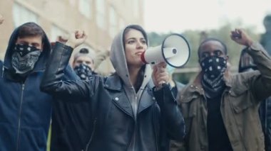Kafkasyalı genç bir kadın megafonla sloganlar atıyordu. Karışık ırk erkek ve kadın protestocular slogan atıp protesto ediyorlar. Eşitlik tezahüratında başı çeken kız.