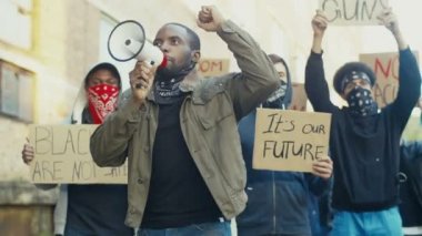 Çok ırklı protestocular ve megafonla bağıran sloganlar arasında protesto yapan Afro-Amerikalı genç yakışıklı adam. İnsan hakları tezahüratında başı çeken adam.