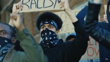 Melez erkek ve kadın öğrencilerin yüzlerinde maskeler, ellerinde posterlerle ırkçılığa ve şiddete karşı protesto gösterileri var. ABD 'deki gösteride çok ırklı kalabalık.