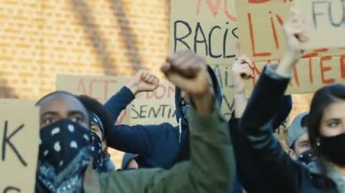 Irkçılık ve polis şiddetini protesto eden maskeli kadın ve erkek protestocular. Amerika 'daki gösterilerde insanların sloganlarını bağıran posterlerle karışık ırklar. İnsan hakları aktivistleri
