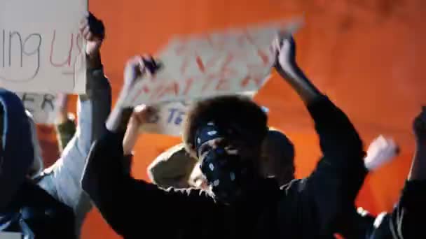 Jeunes manifestants de races mixtes masculines et féminines avec des affiches contre le racisme manifestant dans la rue la nuit. Les rebelles multiethniques crient et crient leurs revendications en plein air. — Video