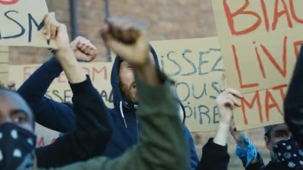 白人年轻的男性反叛者站在多种族的抗议者人群中，用扩音器高喊口号。支持平等人权和反对警察暴力的示威活动中的男性抗议者. — 图库视频影像