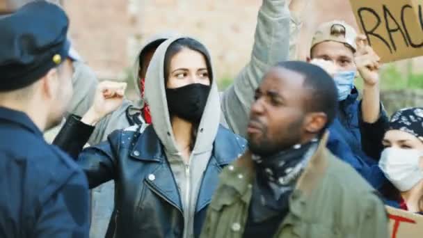 La retaguardia del policía caucásico y del manifestante afroamericano luchando y peleando en la calle durante la manifestación. Conflicto entre policías y manifestantes multiétnicos masculinos y femeninos. Al aire libre . — Vídeos de Stock