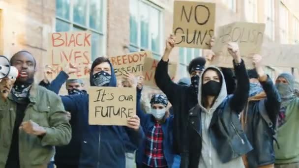 Africano americano jovem líder ativo de protesto contra o racismo andando na rua e levando mestiços homens e mulheres pessoas enquanto gritando slogans em megafone. Manifestação EUA . — Vídeo de Stock