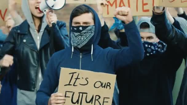 Multiethnic young male and female protesters in masks protesting against racism and police violence. Mixed-races rebels with posters shouting slogans at manifestation in USA. Political activists. — Stock Video