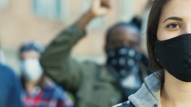 Primo piano di mezza faccia della giovane donna caucasica bella in maschera nera guardando dritto alla macchina fotografica all'aperto a rivolta di strada. Ritratto di ragazza. Manifestante femminile alla manifestazione per i diritti umani. — Video Stock