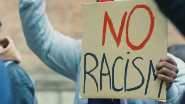 Close up of poster No racism in hands of African American male protester. Face of young beautiful Caucasian woman at manifestation. Mixed-races people at protest. — Stock Video