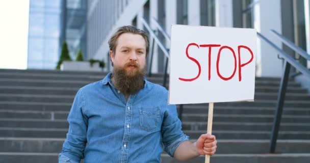 Porträtt av vit manlig aktivist med skägg innehar affisch Stopp vid politisk eller miljömässig ensam demonstration. En enda protest utanför. Aktivism koncept. Människan protesterar ensam. — Stockvideo