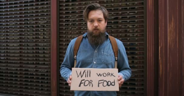 Potret pemuda Kaukasia yang mendemonstrasikan poster dengan kata-kata akan bekerja untuk makanan. Aktivis pria menunjukkan papan dengan mencari pekerjaan pengumuman. Kesepian memprotes. Setelah pengangguran dikunci. — Stok Video