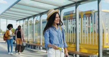 Beyaz, şapkalı, dışarıda yürüyen ve tekerlekli bavul taşıyan güzel bir kadın. Otobüste gezen, tramvayda durup gülümseyen güzel bir bayan turist. Yakışıklı adama merhaba demek için..
