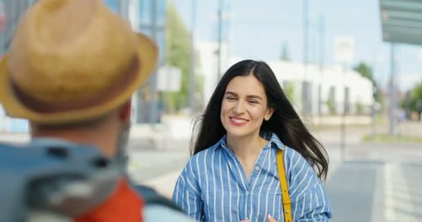 Bella caucasica giovane donna bruna sorridente e incontrare fidanzato o marito all'aperto alla fermata dell'autobus. Torno a casa dopo il viaggio. Coppia innamorata incontrare Posteriore di ragazzo viaggiatore abbracciare fidanzata Close up — Video Stock