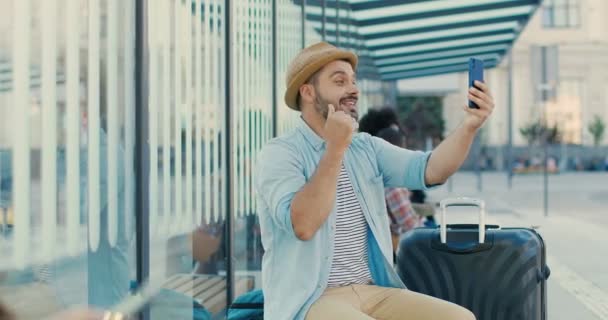 Caucasien jeune homme gai touriste parler, agitant la main et souriant à la caméra smartphone en plein air le jour de l'été. Beau voyageur masculin ayant vidéochat sur la webcam du téléphone. Concept de vidéochat. — Video