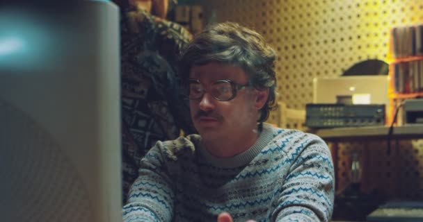 Pria kaukasia berkacamata dan gaya retro merokok di depan monitor lama PC di kamar 80-an. Teknisi pria dari tahun 70-an bekerja pada komputer dan mengetik. Pria masa lalu. — Stok Video