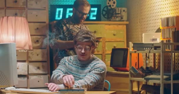 Hackers masculins rétro caucasiens travaillant dans l'intérieur vintage de la pièce. Homme à lunettes assis à un vieil ordinateur et fumant de la cigarette au bureau. Collègue donnant disquette avec des informations. Programmeurs des années 80 — Video