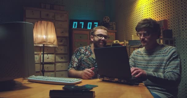 백인 남성 괴짜들이 테이블에 앉아서 컴퓨터로 이야기하고 일하고 있습니다. 두 명의 초기의 젊은 남자들이 키보드로 타자를 치며 공부하고 설명하고 있습니다. 90 년 대 빈티지 스타일. 80 년 대친구들. — 비디오
