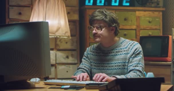 Portrait d'un homme caucasien fou dans des lunettes avec une moustache assis au bureau dans une salle rétro et travaillant sur ordinateur. Programmateur homme drôle regardant la caméra et tapant sur le clavier. Style vintage. — Video