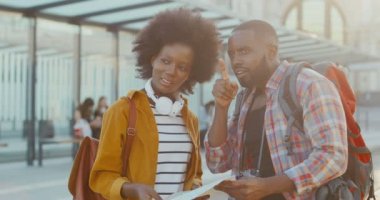 Afro-Amerikalı iki genç turist otobüs durağında durup konuşuyorlar ve nakil için bekliyorlar. Şehir haritası olan güzel bir kadın ve planlama rotası olan yakışıklı bir adam. Yolcu yolu soruyor. Gezginler.