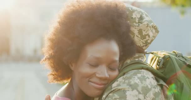 若い幸せなアフリカ系アメリカ人のカップルの愛の出会いと路上で屋外で抱擁のクローズアップ。ハンサムな男兵士が戻ってきてガールフレンドを受け入れる。軍から少女に戻る軍の男. — ストック動画