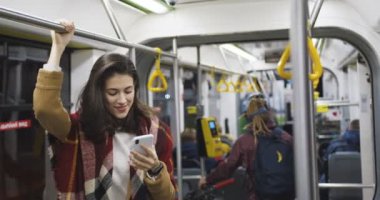 Paltolu ve atkılı zarif beyaz kadın toplu taşıma aracında duruyor ve akıllı telefondaki mesajlarla sohbet ediyor. Çekici kız gece eve dönerken telefonla konuşuyor ve kayıyor..