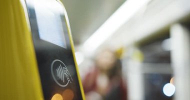 Tramvay ya da otobüs biletlerinin sarı bluetooth tarayıcısını kapat. Toplu taşıma parasını ödemek için akıllı telefonu tarayan bir kadın. Telefonla ödeme. Yolculuk için ödeme yapan kız.