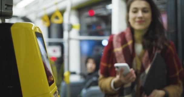 Närbild av gul bluetooth skanner av biljetter i spårvagn eller buss. Kvinna skanning smartphone för att betala för kollektivtrafik. Betalning per telefon. Flicka betalar för resan. — Stockvideo