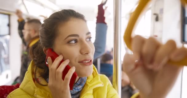 Hermosa joven caucásica feliz mujer de pie en autobús y hablando por teléfono celular. Pasajera alegre del transporte público hablando por teléfono móvil. Chica sonriente teniendo una buena llamada en tranvía. De cerca. . — Vídeos de Stock