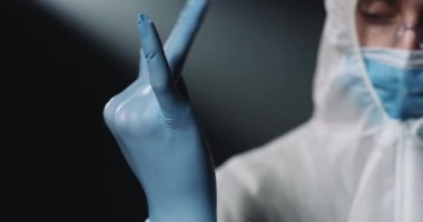 Gözlüklü, tıbbi maskeli, koruyucu kostümlü, mavi lastik eldivenli ve Coronavirus 'la çalışmaya hazırlanan Kafkasyalı doktorları yakın çekim yapın. Koruma konsepti doktoru.