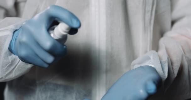 Sluiten van de handen in blauwe rubberen handschoenen van de arts. Medic sproeien ontsmettingsmiddel op handen en verspreiden. Schoonmaakconcept. Dokter epidemioloog doodt bacteriën. — Stockvideo