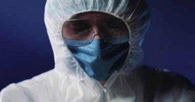 Tıbbi maskeli ve koruyucu gözlüklü, cam test tüpünü kanla tutan ve kameraya gösteren tam donanımlı ve koruyucu doktorlara yakın durun. Covid-19 pozitif test. Sıhhiye teşhisi koydu.