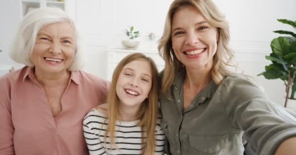 Vacker vit tre kvinnliga generationer. Ganska glad kvinna med tonåring liten dotter och senior mor pratar med kameran och videochattar inomhus. Födelsedatum: Videochatt på webbkamera med mormor. — Stockvideo