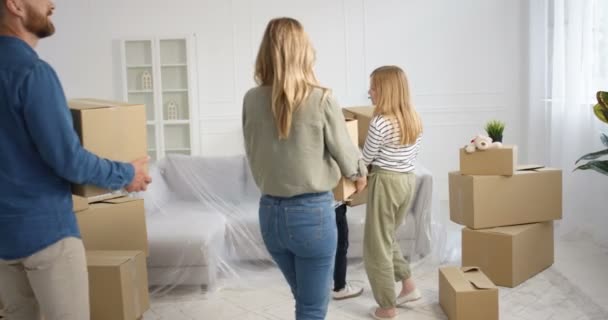 Caucasian happy family with kids coming in new home and carrying carton boxes. Mother, father with kids entering house after repairment and looking around with smiles. Parents and children moving in. — Stock Video
