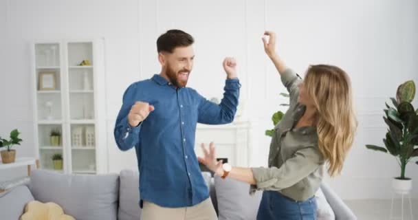 Joyeux Caucasien jeune couple vient de se marier s'amuser et danser dans le salon confortable. Belle femme heureuse et bel homme dansent et rient. Le bonheur de la femme et du mari. À l'intérieur. Concept d'amour. — Video