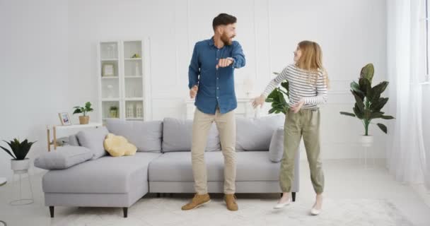 Cheerful happy young Caucasian father dancing with cute little teen daughter and having fun in cozy living room. Dad playing with kid at home. Pretty small teenage girl laughing and dance. — Stock Video