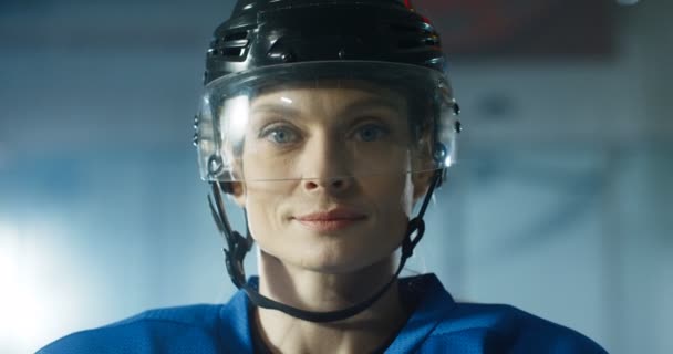 Primer plano de feliz hermosa joven caucásica jugador de hockey femenino en el casco sonriendo alegremente y respirando con vapor en la arena de hielo. Retrato de bonita deportista alegre . — Vídeos de Stock