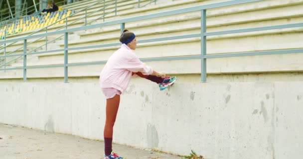 Vrij alleen Kaukasisch vintage meisje in roze ouderwetse jas trekken sokken terwijl buiten. Mooie stijlvolle jonge vrouw uit de jaren 70 poseren in het stadion op straat. Concept in retrostijl — Stockvideo