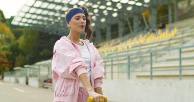 Pembe takım elbiseli, açık havada çalışan beyaz, mutlu, genç bir kız. Retro stili güzel, neşeli bayan sporcu egzersiz yapıyor ve caddede yükselen dambıllar. Spor tarzı konsepti