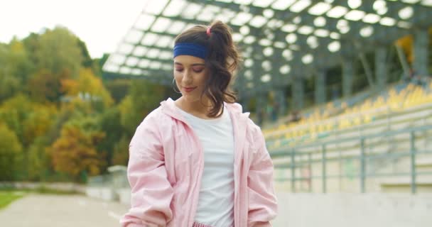 Retro stijl mooie vintage sportvrouw doen oefening op biceps met kleine halters op straat. Portret van een grappig, blank meisje in een roze jasje dat buiten aan het trainen is. Sportconcept — Stockvideo