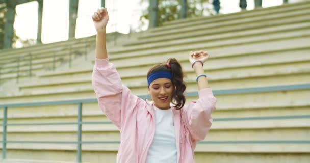 Portrait of beautiful joyful Caucasian young vintage female in pink jacket dancing and jumping outdoors. Cukup senang gadis dalam suasana hati yang baik menggerakkan tangannya mengangkat dan tersenyum di jalan. Konsep retro — Stok Video