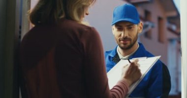 Postacıdan gelen paket teslimatı sırasında beyaz bir kadının panoya imza atması..