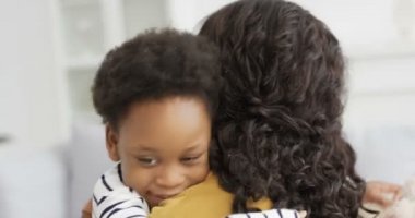 Mutlu, Afro-Amerikan bir kadının arka koltuğunda küçük şirin kızına sarılışı. Anne kıvırcık saçlı, küçük çocuk oturma odasında. Annenin gülümseyişine ve kucak açan çocuğuna bakıyorum..