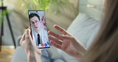 Kafkasyalı doktorla evde akıllı telefondaki video konferansında görüşen bir kız. Doktor, kadın hasta doktoruna cep telefonuyla görüntülü konuşma gösteriyor. Sağlık hizmetleri kavramı