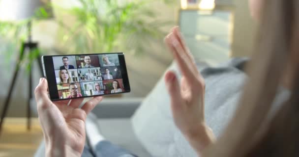 Donna che parla con diversi colleghi in videoconferenza su smartphone mentre riposa in camera. Conversazione con dipendenti felici multietnici attraverso la fotocamera del cellulare in videochiamata online concetto di lavoro — Video Stock