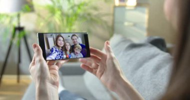 Kız, evden cep telefonuyla elini sallıyor ve mutlu beyaz bir aileyle görüntülü sohbet ediyor. Neşeli arkadaşları ve çocukları ile video konferansında konuşan bir kadın. Çevrimiçi sohbet kavramı